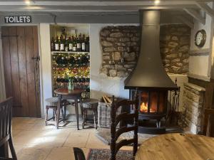 Habitación con chimenea y mesa con sillas y botellas de vino. en The Talbot Inn en Eynsham