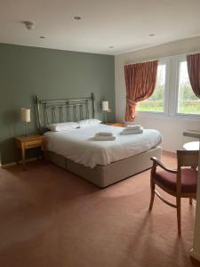 a bedroom with a bed and a chair and a window at The Conningbrook Hotel in Ashford