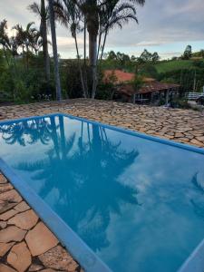 a swimming pool with blue water and rocks at Pousada Recanto Alegre in Campestre