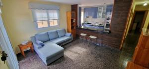 uma sala de estar com um sofá azul e uma cozinha em VV EL OASIS em Tamaduste