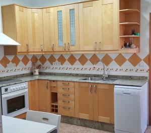 a kitchen with wooden cabinets and a sink and a dishwasher at Casa para vacaciones o estancias cortas in Barrio de las Cuevas