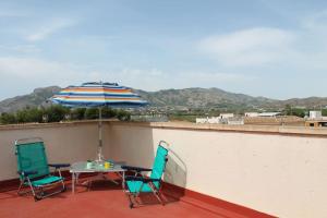 two chairs and a table with an umbrella on a roof at Casa para vacaciones o estancias cortas in Barrio de las Cuevas