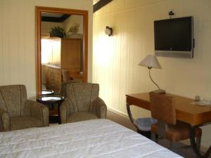 Habitación de hotel con cama, escritorio y TV. en The Amethyst Beach Motel en Point Pleasant Beach