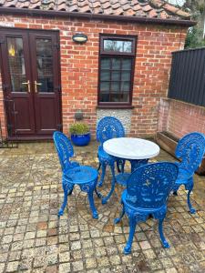 four blue chairs and a table in front of a brick house at The Old Stables in Mews in Kessingland