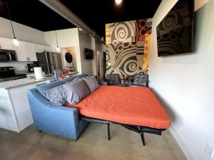 BNA Carpet Condo - 4 miles to DT في ناشفيل: أريكة زرقاء مع وسادة برتقال في المطبخ