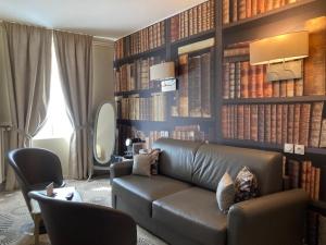 a living room with a leather couch and books at Hotel Le Lion D'Or et Restaurant La Table Du Lion in Bayeux