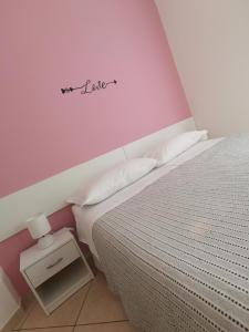 a bedroom with a bed and a pink wall at BeB I PORTICI in Cernobbio