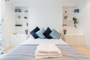 a bedroom with a bed with blue and white pillows at Beautiful Home in Camden with Garden in London