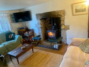 uma sala de estar com uma lareira de pedra e um sofá em Corndonford farm em Newton Abbot