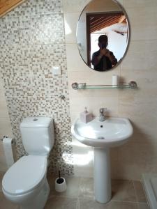 een badkamer met een toilet, een wastafel en een spiegel bij George's Studios in Ermones