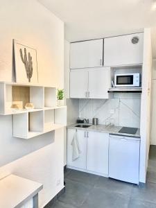 a kitchen with white cabinets and a microwave at Studio à deux pas de la mer in Nice