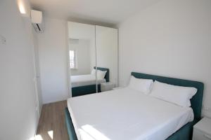 um quarto com uma cama branca e um espelho em D Suite Fronte Mare em San Benedetto del Tronto