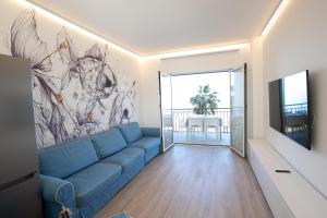uma sala de estar com um sofá azul e uma pintura na parede em D Suite Fronte Mare em San Benedetto del Tronto