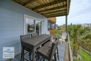a porch with a wooden table and chairs on a house at The Salted Rim in North Topsail Beach