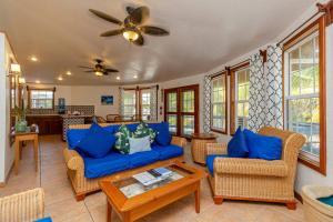 sala de estar con muebles azules y ventilador de techo en White Sands Cove, en San Pedro