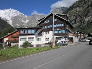 un bâtiment situé sur le côté d'une route avec une montagne dans l'établissement Hotel Nuovo Pecetto, à Macugnaga