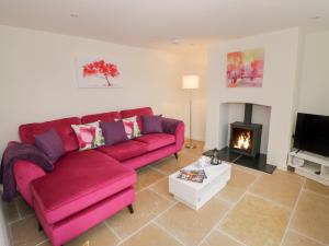 a living room with a red couch and a fireplace at Old Farm Cottage in Upper Sapey