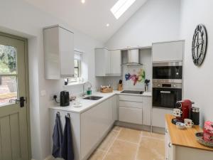 a white kitchen with white cabinets and a table at Old Farm Cottage in Upper Sapey