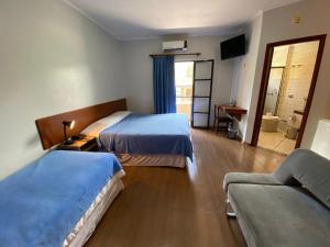 um quarto de hotel com duas camas e um sofá em Minas Garden Hotel em Poços de Caldas