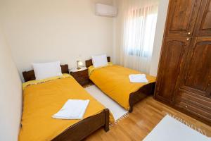 two beds in a small room with yellow sheets at Zmas Apartment in Chorto