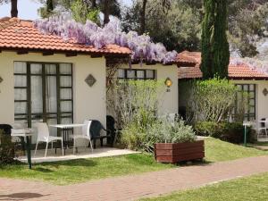 a house with a table and chairs and purple wisterias at Shoresh Green Hills in Shoresh