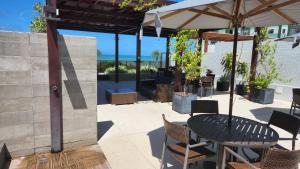 a patio with a table and chairs and an umbrella at COBERTURA VISTA MAR in João Pessoa
