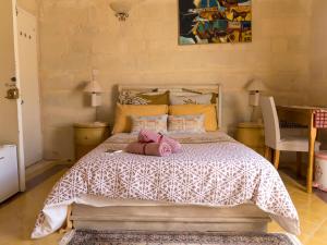 um quarto com uma cama com um bicho de peluche cor-de-rosa em The Knight - Historical terraced house overlooking the central square em Birgu