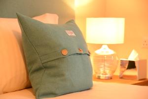 a green pillow sitting on a bed with a lamp at Torlinnhe Guest House in Fort William