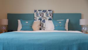 a bed with a blue blanket and pillows on it at Torlinnhe Guest House in Fort William