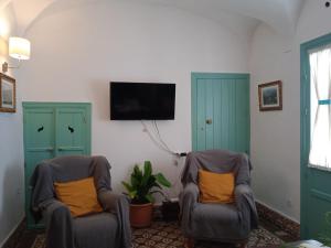 salon z 2 krzesłami i telewizorem z płaskim ekranem w obiekcie Casa de las Bóvedas w mieście Rosal de la Frontera