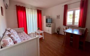 a living room with red curtains and a couch at Apartments Štokić in Rab