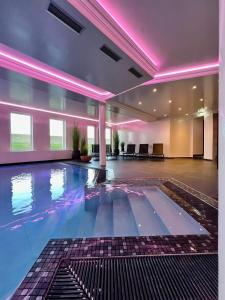 a large swimming pool in a building with purple lights at meergut HOTELS in Kühlungsborn