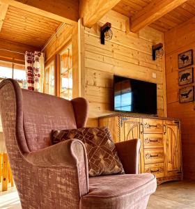 una sala de estar con sofá y TV en una cabaña en Osada Podrazówka, en Zakopane