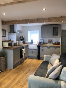 a living room with a couch and a kitchen at Honeybee Cottage, Waddington in Waddington