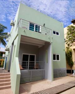 a green house with a balcony on the side at MeMe's Place in Placencia Village