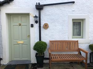 a bench in front of a house with a green door at Honeybee Cottage, Waddington in Waddington