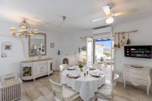 a white dining room with a table and a mirror at Mykonos Psarou Place in Psarou