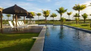 a swimming pool with chairs and an umbrella and palm trees at Condominio Mediterraneo - Iberostate in Praia do Forte