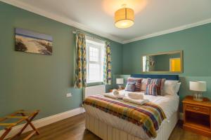a bedroom with a bed with blue walls and a window at Redwings Sanctuary Rooms - Norfolk Holiday Properties 