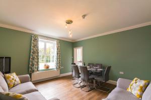 a living room with green walls and a table and chairs at Redwings Sanctuary Rooms - Norfolk Holiday Properties 