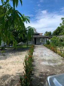 una entrada que conduce a una casa con flores en Casa com piscina em Barra de Jacuípe BA, en Barra do Jacuípe