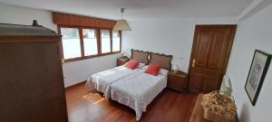 Un dormitorio con una cama con almohadas rojas. en Casa Rural El Puente de Agues, en Soto De Agues
