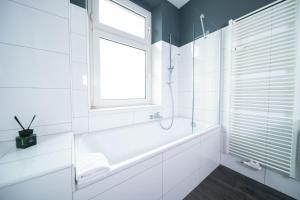 a white bathroom with a tub and a window at Favorite Stays - Suite And More - Kitchen in Neuss