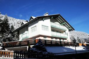 a building with snow on the ground in front of it at Casa Al Mesdì in Pozza di Fassa