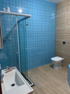 uma casa de banho em azulejos azuis com um WC e um lavatório em Cantinho do Rafa em São Lourenço