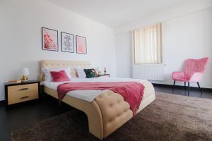 a bedroom with a bed and a pink chair at Plaza Apartment in Satu Mare