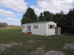 a small white shed in a field with trees at Ferienwohnung Biene in Wiesmoor