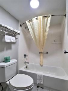 a white bathroom with a toilet and a bath tub at Inn Of Rockwall in Rockwall