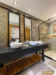 a bathroom with two sinks on a counter with mirrors at Casas Solar dos Pireneus in Pirenópolis