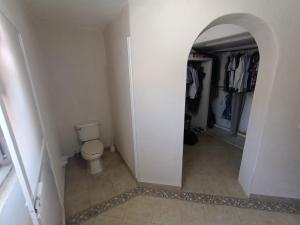 a bathroom with a toilet in a hallway with an archway at Casa Epari in Acapulco
